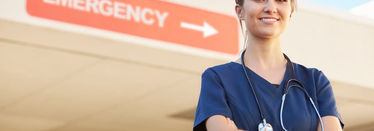 Young nurse standing in front of a sign that says EMERGENCY