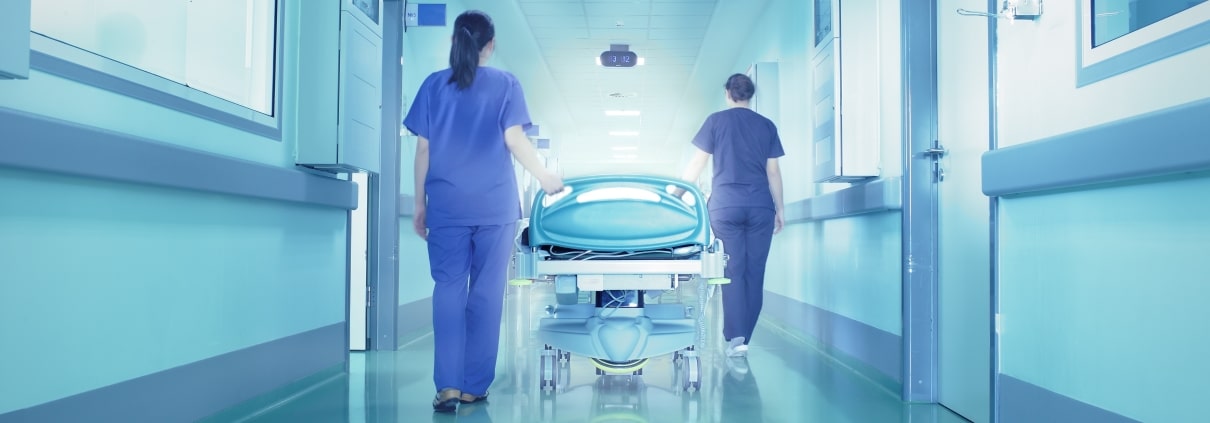 Nurses transporting a patient in a hospital hallway