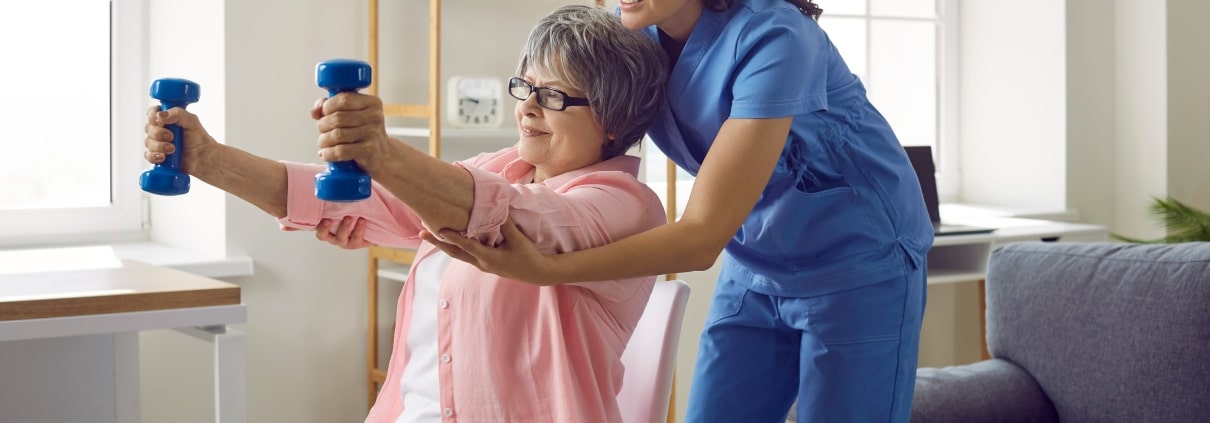 Physical therapy professional helping an older woman lift weights