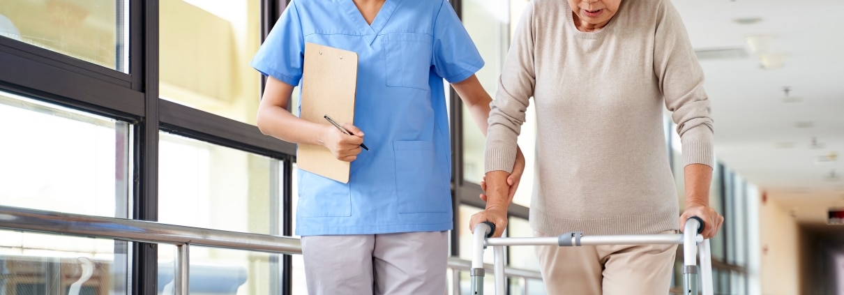 Asian medical professional helping a senior woman use a walker